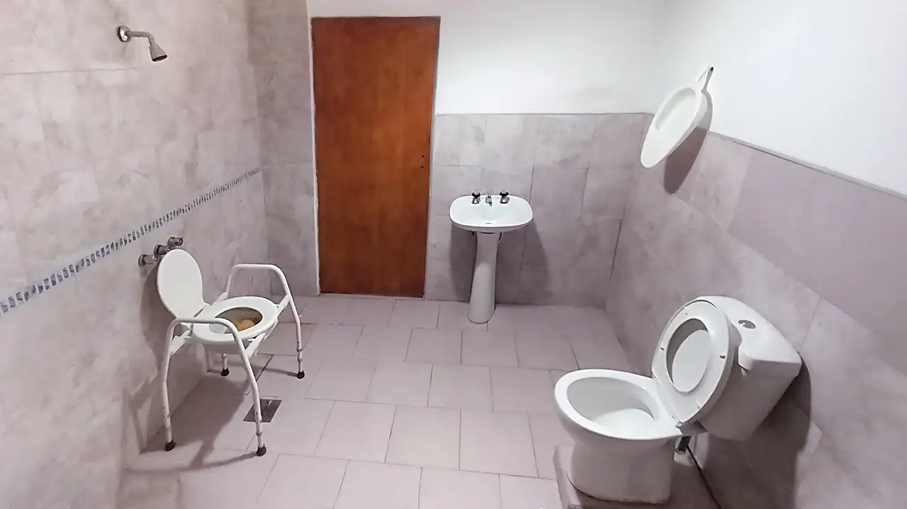 Baño adaptado para adultos mayores con silla de ducha y agarraderas